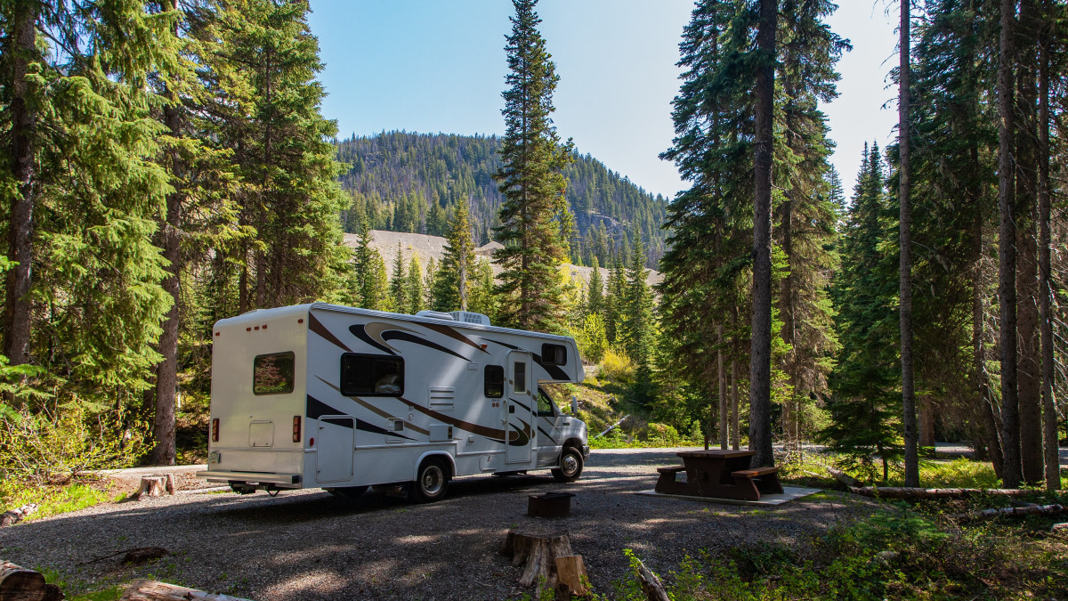 Un camping-car est stationné dans une forêt à côté d'une table de pique nique